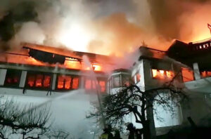 Feuerwehrleute bekämpfen ein großes Feuer in einem Gebäude bei Nacht.
