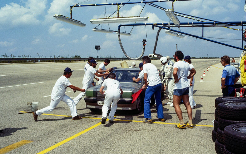 Mehrere Personen arbeiten an einem Auto auf einer Rennstrecke.