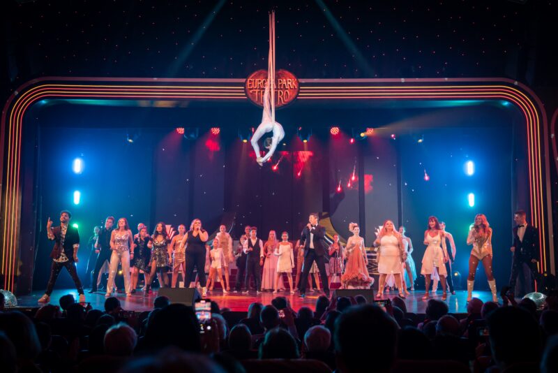 Aerial performer and cast on stage at a theater show.