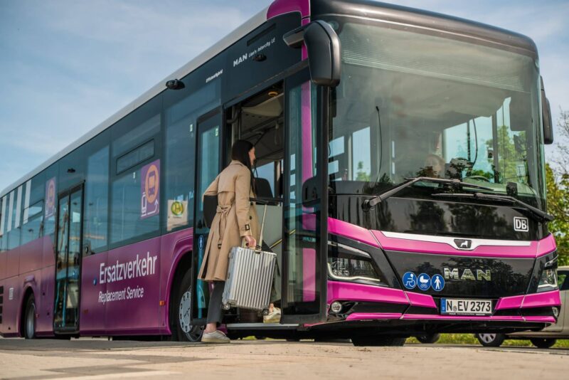 Frau mit Koffer steigt in pinken Ersatzbus ein.