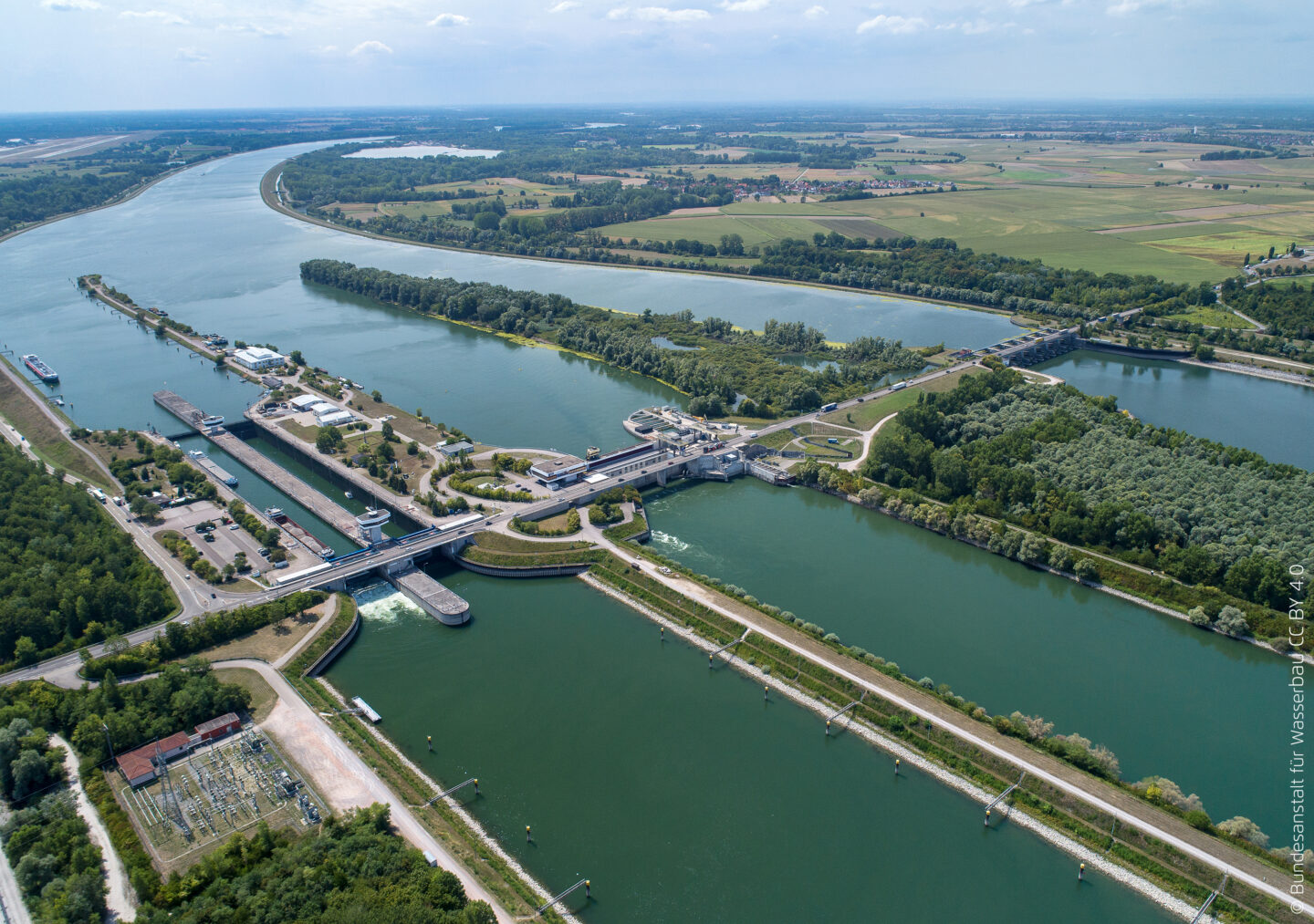 Luftaufnahme eines Wasserkraftwerks mit Flüssen und grüner Landschaft.