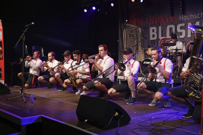 Musiker in Trachtenkleidung spielen auf einer Bühne.