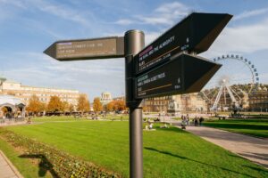 Wegweiser mit Veranstaltungen und Riesenrad im Hintergrund.