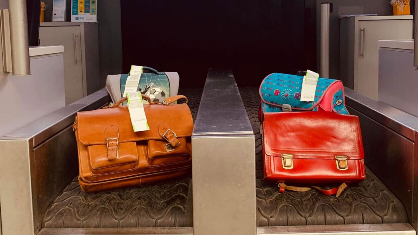 Zwei Taschen auf einem Gepäckband, eine braune und eine rote.