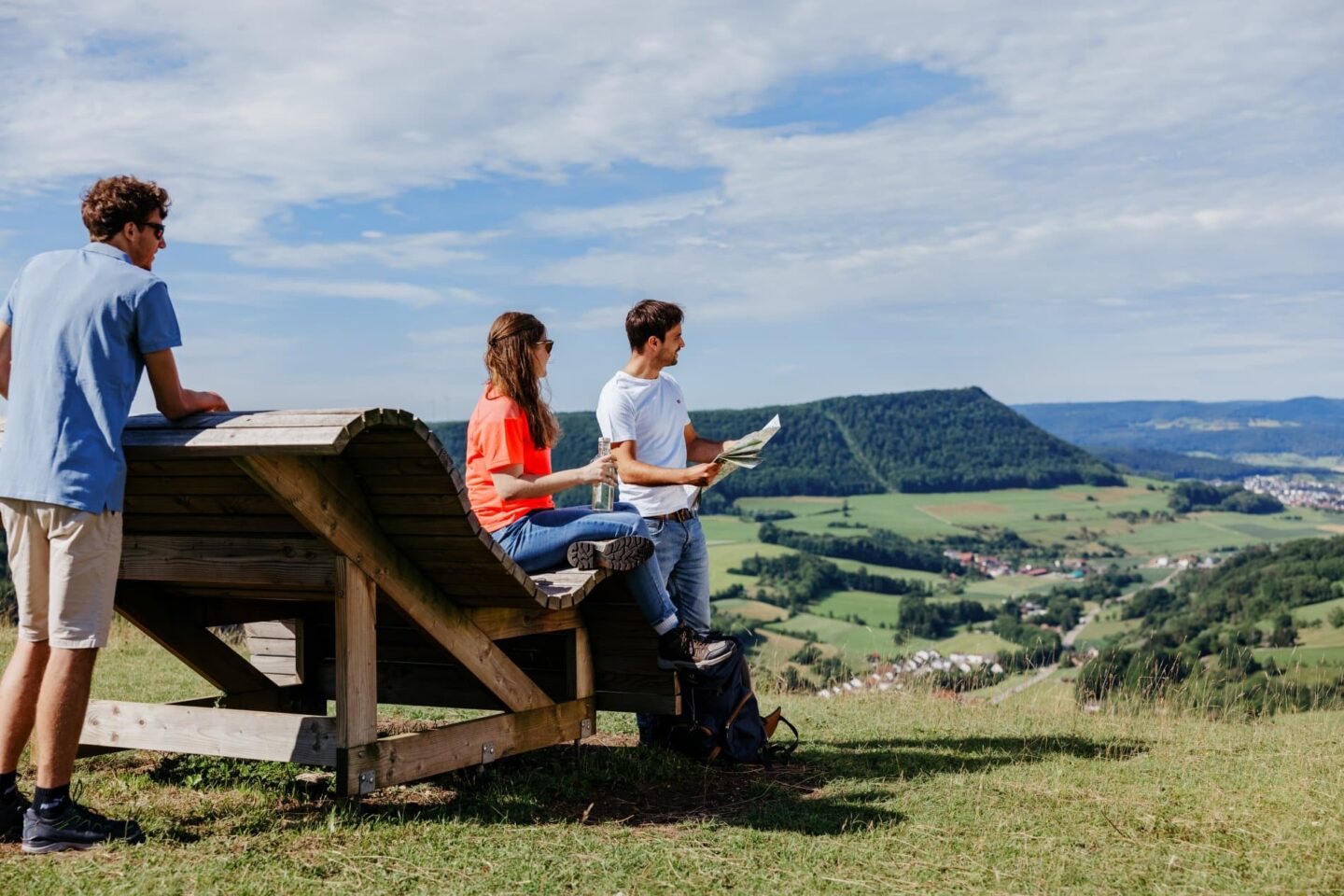 Drei Personen genießen die Aussicht auf eine grüne Landschaft.
