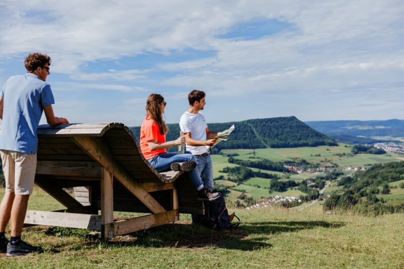 Drei Personen genießen die Aussicht auf eine grüne Landschaft.