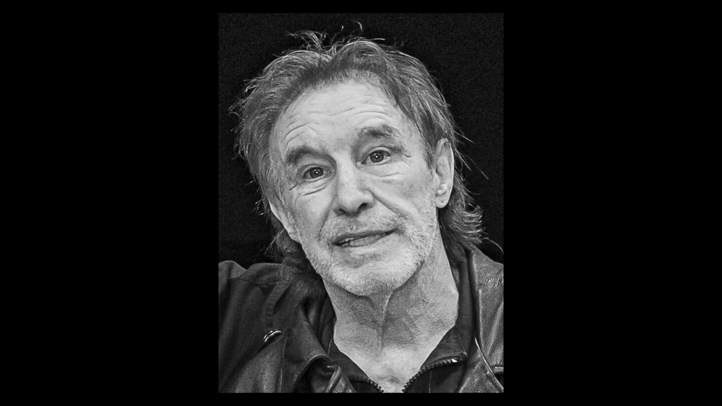 Älterer Mann mit grauen Haaren und Lederjacke, lächelt in die Kamera.