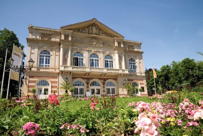 Historisches Gebäude mit Blumenbeet und blauem Himmel.