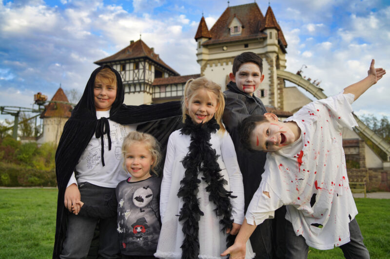 Fünf Kinder in Halloween-Kostümen vor einem Schloss.