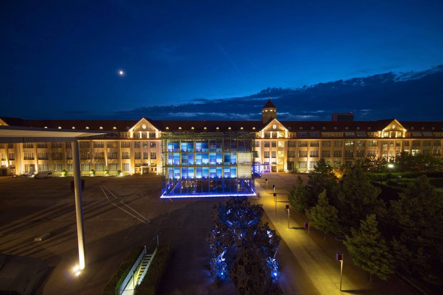 Moderne Architektur bei Nacht mit blauen Lichtern und einem klaren Himmel.