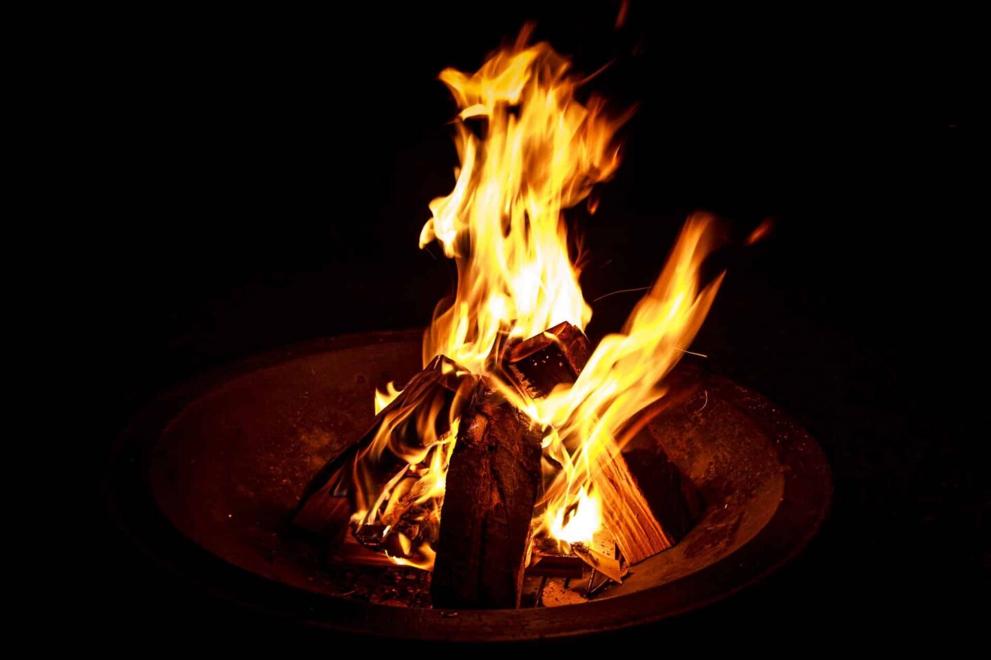 Loderndes Feuer in einer Feuerschale bei Nacht.