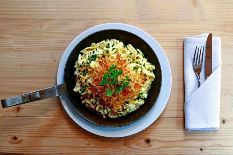 Ein Teller mit Pasta, garniert mit Röstzwiebeln und Kräutern.