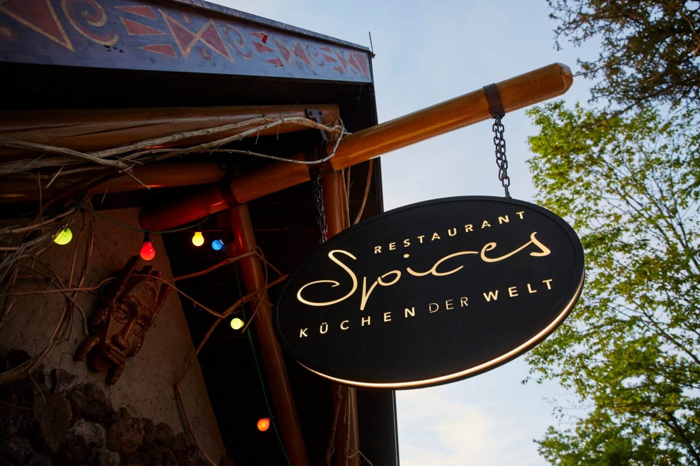 Schild des Restaurants Spices mit bunten Lichtern und dekorativen Elementen.