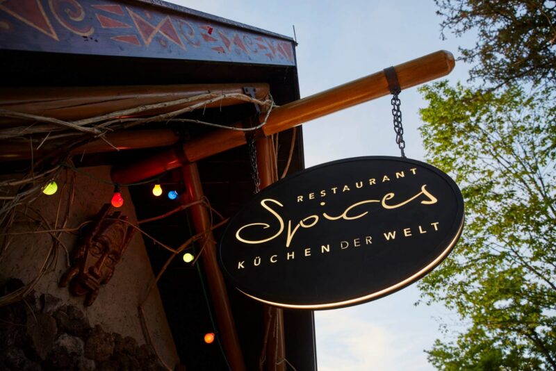 Schild des Restaurants Spices mit bunten Lichtern und dekorativen Elementen.