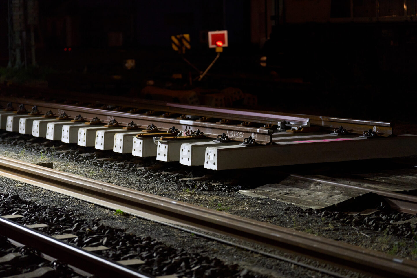Nahaufnahme von Gleisen mit neuen Schwellen bei Nacht.