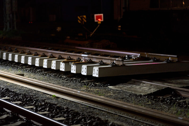 Nahaufnahme von Gleisen mit neuen Schwellen bei Nacht.