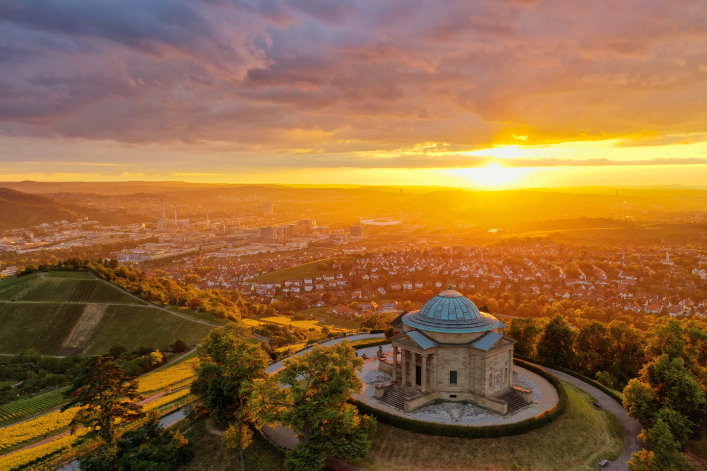 Panoramablick auf ein Denkmal bei Sonnenuntergang über einer Stadtlandschaft.
