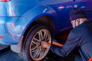 Mann arbeitet an einem blauen Auto in einer Werkstatt.