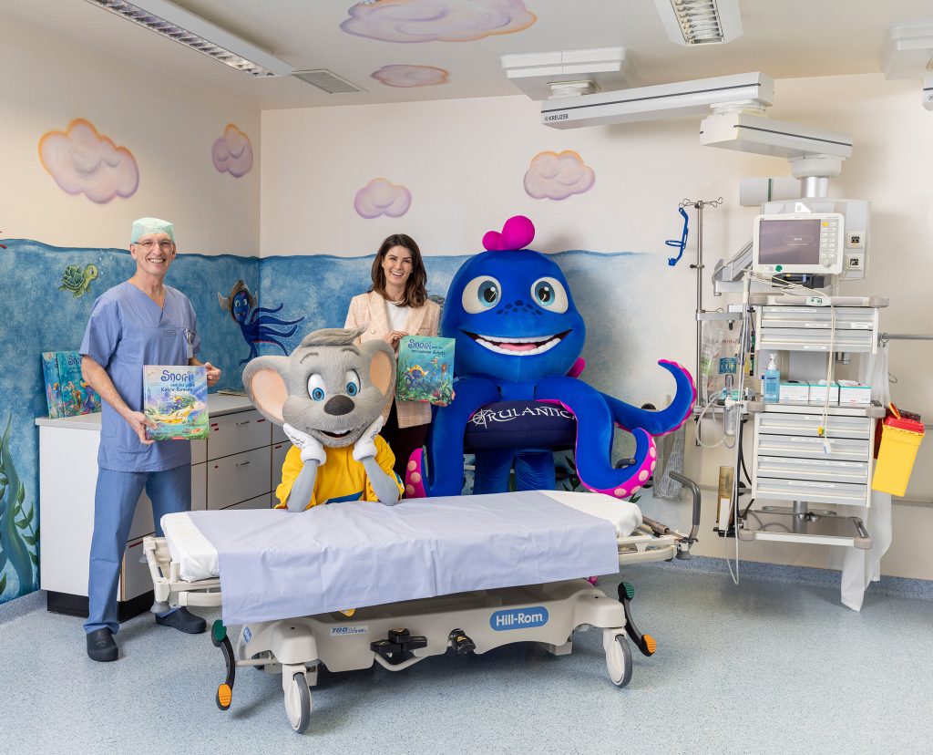 Gemeinsam mit den Maskottchen Snorri und Ed Euromaus besichtigen Prof. Dr. Hartmut Bürkle, Ärztlicher Direktor der Klinik für Anästhesiologie und Intensivmedizin des Universitätsklinikums Freiburg, und Miriam Mack, Soziale und kulturelle Angelegenheiten sowie Head of Corporate Health Mack Gruppe, den neu gestalteten Aufwachraum im Bereich Kinderchirurgie. 