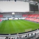 Innenansicht des Europa-Park Stadions in Freiburg, mit grünem Spielfeld, leeren rot-weißen Tribünen und überdachter Konstruktion.