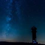 Der Feldbergturm bei Nacht, umgeben von einem klaren Sternenhimmel mit der Milchstraße im Hintergrund.