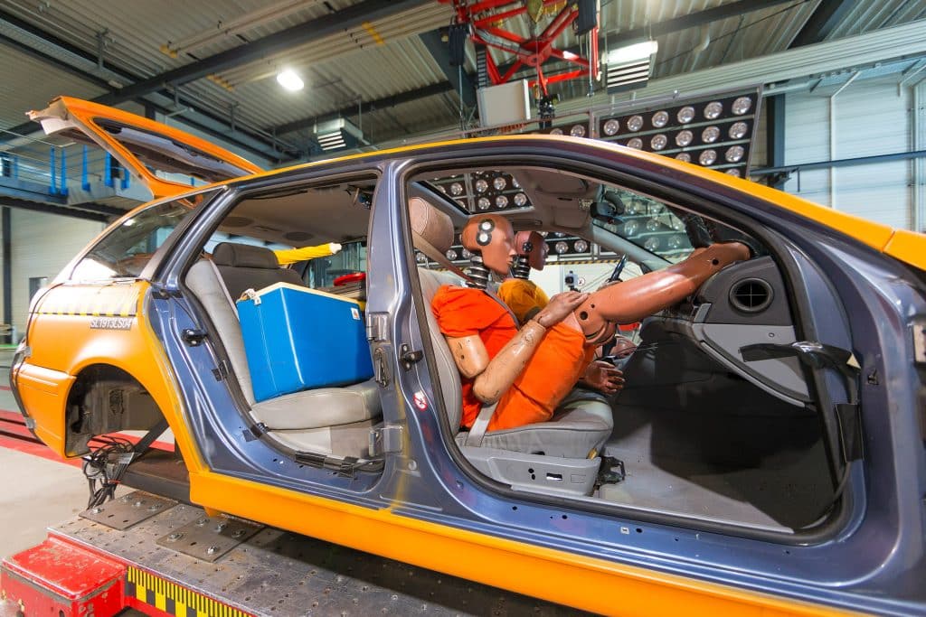 Vorbereitungen Crashtest NICHT angeschnallter Fahrer, Beifahrer angeschnallt mit Fuessen auf Armaturenbrett, ungesicherte Ladung, Crash mit 50 km/h 
