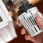 Mann dreht an einem Heizungsthermostat