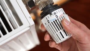 Mann dreht an einem Heizungsthermostat