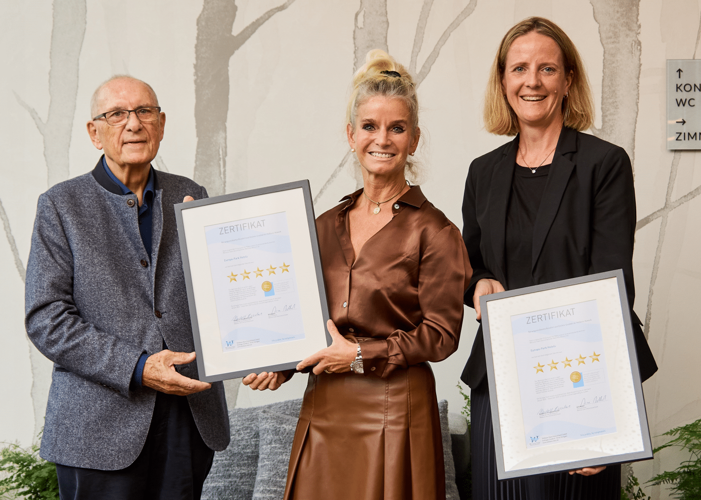 Michaela Doll-Lämmer, Direktorin Europa-Park Hotels (Mitte), und Ulrike Braun, Senior Sales Managerin Europa-Park Hotels, freuen sich über die Wellness Stars Urkunde für die Hotels "Santa Isabel", Colosseo", "Bell Rock" und "Krønasår", überreicht von Prof. Rudolf Forcher, Aufsichtsratsvorsitzender der Wellness Star 
