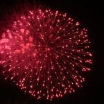 Rotes Feuerwerk am Nachthimmel, mit leuchtenden Lichtstrahlen, die sich radial ausbreiten.