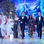 Die Moderatoren Victoria Swarovski und Daniel Hartwich, begleitet von der Jury bestehend aus Jorge González, Motsi Mabuse und Joachim Llambi, beim festlichen Opening der „Let’s Dance – Die große Weihnachtsshow“. Im Hintergrund ist eine winterliche Kulisse mit geschmückten Weihnachtsbäumen zu sehen, während Tänzer:innen für Stimmung sorgen.