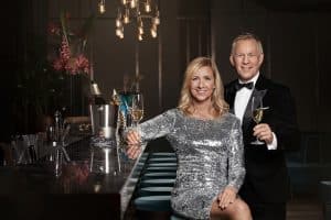 "Willkommen 2025": Andrea Kiewel sitzt an der Bar, sie ist festlich gekleidet. Johannes B. Kerner steht im Smoking neben ihr und hält ein Sektglas in der Hand.