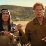 Michael Bully Herbig als Häuptling Abahachi und Christian Tramitz als Ranger stehen in einer typischen Wildwest-Landschaft. Abahachi hält eine traditionelle Friedenspfeife, während Ranger irritiert eine brennende Streichholzschachtel betrachtet. Die Szene ist humorvoll inszeniert und vermittelt den typischen Stil von „Das Kanu des Manitu“. Im Hintergrund sind Wüstenhügel und blauer Himmel zu sehen.