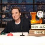 Michael Bully Herbig steht lächelnd vor dem Set von „LOL: Last One Laughing“, mit Logo und Prime Video Branding im Hintergrund.