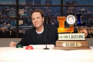 Michael Bully Herbig steht lächelnd vor dem Set von „LOL: Last One Laughing“, mit Logo und Prime Video Branding im Hintergrund.