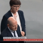 Screenshot aus einer Phoenix-Live-Übertragung im Bundestag. Im Vordergrund Bundeskanzler Olaf Scholz, der nach unten schaut, während er mit Rolf Mützenich vorbeigeht. Im Hintergrund Saskia Esken, die sichtlich irritiert wirkt und in Richtung der beiden schaut. Einblendung unten zeigt: "Kommentar: Gerd-Joachim von Fallois - Bundeskanzler Scholz hat im Bundestag di
