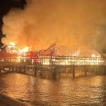 Die Rorschacher Badhütte am Schweizer Bodenseeufer brennt in der Nacht lichterloh, während Flammen und dichte Rauchwolken das hölzerne Stelzengebäude erfassen.