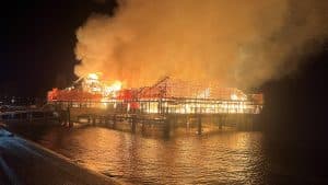 Die Rorschacher Badhütte am Schweizer Bodenseeufer brennt in der Nacht lichterloh, während Flammen und dichte Rauchwolken das hölzerne Stelzengebäude erfassen.