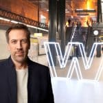 "Marcus Niehaves, Moderator des ZDF-Wirtschaftsmagazins 'WISO', steht in einer modernen U-Bahn-Station mit einem großen, beleuchteten 'W' im Hintergrund. Die Szene ist warm beleuchtet, und Menschen bewegen sich im Hintergrund die Rolltreppen hinauf."