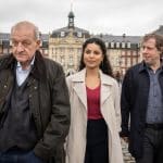 "Wilsberg - Über dem Gesetz": Wilsberg (Leonard Lansink), Dr. Tessa Tilker (Patricia Meeden) und Ekki Talkötter (Oliver Korittke) laufen über den Vorplatz eines Schlosses. Die Fassade des historischen Gebäudes erhebt sich im Hintergrund.