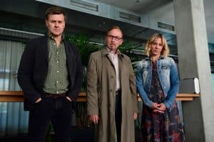 "München Mord - Nix für Angsthasen": Harald Neuhauser (Marcus Mittermeier), Ludwig Schaller (Alexander Held) und Angelika Flierl (Bernadette Heerwagen) stehen in einem Raum vor einer Fensterfront mit zugezogenen Vorhängen und schauen grimmig in die Kamera.