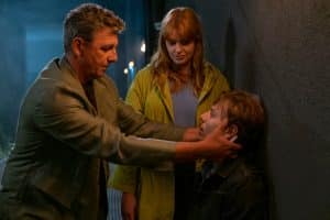 "Der Bergdoktor: Zwei Gesichter": Im Hinterhof des Festspielhauses am Abend: Benommen sitzt Oskar Lenz (Max Schimmelpfennig) auf einer Kiste und wird von Dr. Martin Gruber (Hans Sigl) untersucht. Emily Scheffler (Lilly Charlotte Dreesen) steht neben ihm und lächelt Oskar aufmunternd an.