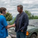 "Der Bergdoktor: Kindeswohl": Vor dem Haus der Familie Fischer: Vor dem grünen Mercedes stehen sich Dr. Martin Gruber (Hans Sigl) und John Luckau (Nico Marischka) gegenüber und reichen sich die Hände. Dr. Gruber lächelt den Jungen aufmunternd an.