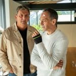 "Der Bergdoktor: Unverzeihlich": Im Haus von Gero Jung: Nachdenklich, beide Hände in den Hosentaschen, steht Dr. Martin Gruber (Hans Sigl) neben Gero Jung (Harry Blank). Dieser blickt entschlossen aus dem Fenster. An seiner Stirn klebt ein Pflaster und an seiner Hand trägt er eine Manschette.