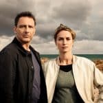Hendrik Duryn als Hauptkommissar Tjark Wolf und Pia Barucki als Hauptkommissarin Femke Folkmer stehen in einer Küstenlandschaft mit Dünen und stürmischem Himmel.