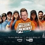 Offizielles Key-Visual zu „MISSION UNKNOWN: Atlantik“. Knossi steht in der Mitte, umgeben von den Teilnehmern der Show, die in zwei Teams aufgeteilt sind – Team Blau und Team Orange. Im Hintergrund das offene Meer, im Vordergrund das Logo der Sendung. Zwei Segelboote auf stürmischer See symbolisieren die Herausforderung. Darunter die Streaming-Termine: Ab 28. Februar bei Prime Video, ab 16. März auf YouTube.