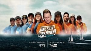 Offizielles Key-Visual zu „MISSION UNKNOWN: Atlantik“. Knossi steht in der Mitte, umgeben von den Teilnehmern der Show, die in zwei Teams aufgeteilt sind – Team Blau und Team Orange. Im Hintergrund das offene Meer, im Vordergrund das Logo der Sendung. Zwei Segelboote auf stürmischer See symbolisieren die Herausforderung. Darunter die Streaming-Termine: Ab 28. Februar bei Prime Video, ab 16. März auf YouTube.