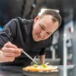 Alexander Mayer, neuer Head Chef des Eatrenalin, konzentriert sich in einer modernen Restaurantküche darauf, ein Gericht mit Präzision anzurichten.