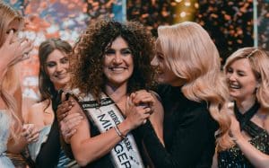 Apameh Schönauer, die Gewinnerin von Miss Germany 2024, wird von Mitfinalistinnen und Moderatorin Lola Weippert umringt und gefeiert. Die Szene zeigt die emotionale Krönung der Siegerin auf der Bühne des Europa-Parks Rust, begleitet von Konfetti und jubelnden Teilnehmerinnen.
