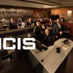 NCIS“-Promo-Bild: Das Ermittlerteam in einem Büro mit Schreibtischen und Computern. Im Fokus stehen die Charaktere der Serie, umgeben von Akten, Pinnwänden und einer professionellen Arbeitsumgebung. Der Schriftzug „NCIS“ ist prominent im Vordergrund platziert.